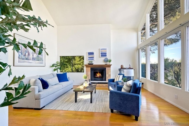 living room with a tile fireplace, high vaulted ceiling, and light wood-type flooring