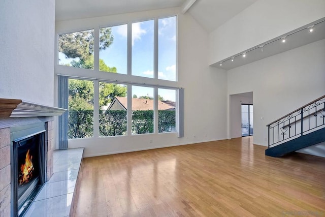 living room with beam ceiling, high vaulted ceiling, and light hardwood / wood-style flooring