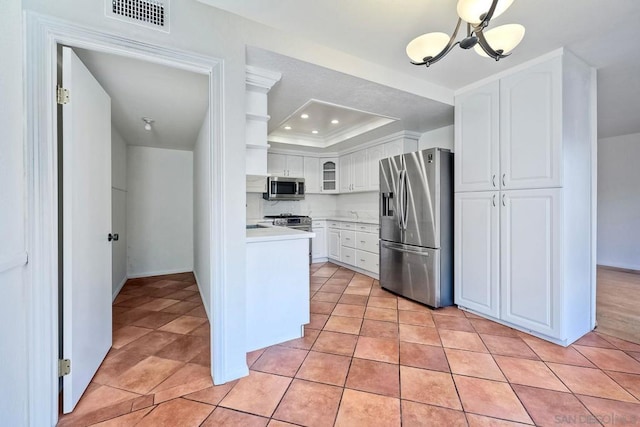 kitchen featuring light tile patterned floors, stainless steel appliances, a raised ceiling, and white cabinets