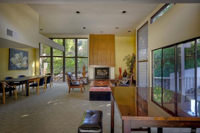 carpeted living room featuring a large fireplace and a high ceiling