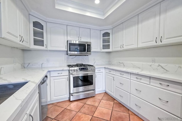 kitchen featuring stainless steel appliances, crown molding, white cabinets, and a tray ceiling