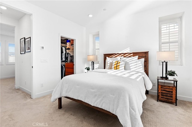 bedroom featuring light carpet, a walk in closet, and a closet