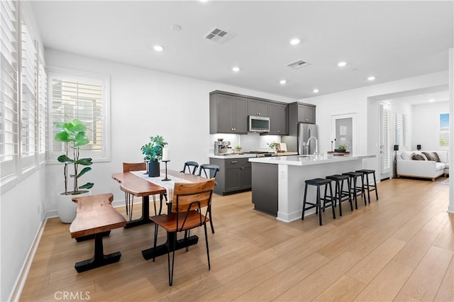 kitchen with a center island with sink, a wealth of natural light, gray cabinets, and appliances with stainless steel finishes