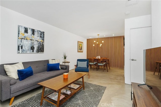 living room with an inviting chandelier and wooden walls