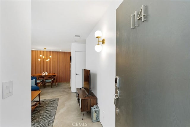 hall featuring an inviting chandelier and wooden walls