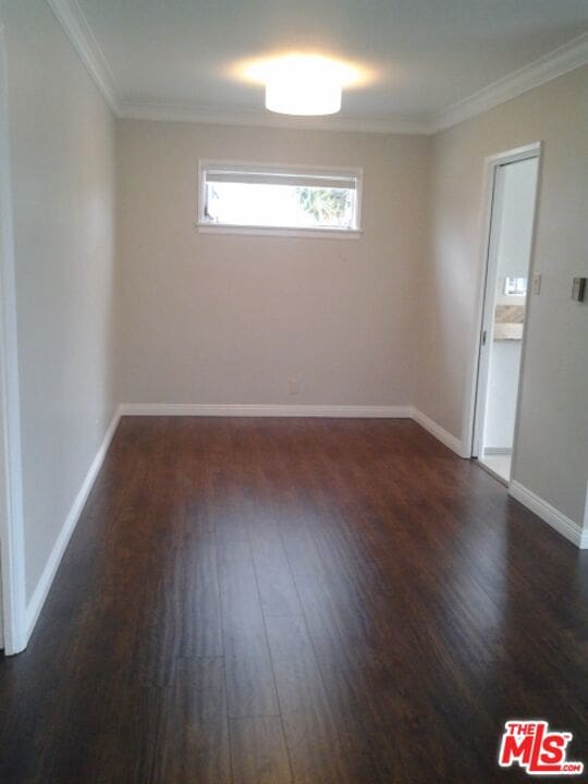 empty room featuring dark hardwood / wood-style flooring and ornamental molding