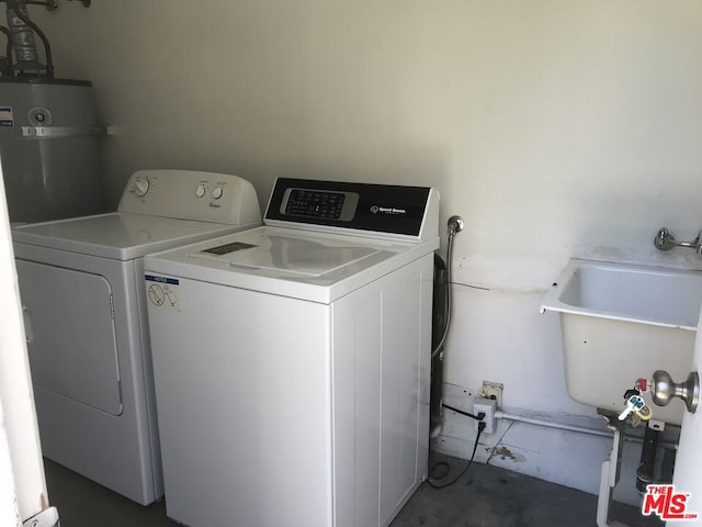 washroom featuring secured water heater, washer and clothes dryer, and sink