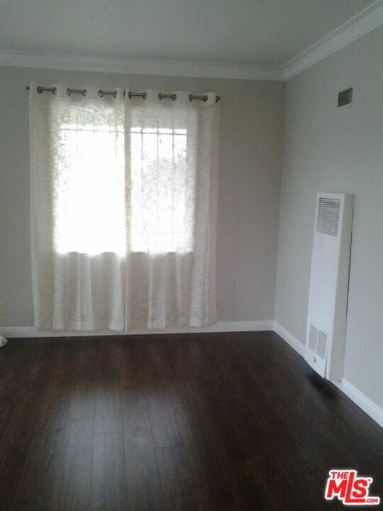 unfurnished room with crown molding and dark hardwood / wood-style flooring