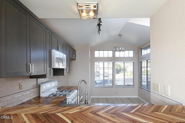 kitchen featuring white appliances, an inviting chandelier, sink, vaulted ceiling, and dark hardwood / wood-style floors