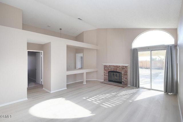 unfurnished living room featuring a fireplace, high vaulted ceiling, and light hardwood / wood-style flooring