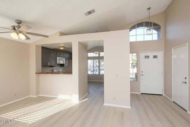 foyer entrance with a textured ceiling, light hardwood / wood-style floors, ceiling fan, and lofted ceiling