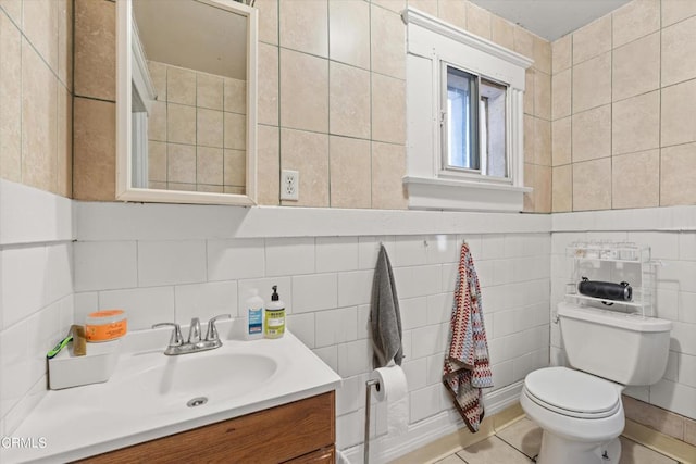 bathroom with tile patterned flooring, vanity, toilet, and tile walls