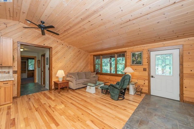 living room featuring lofted ceiling, light wood-type flooring, wooden walls, and wood ceiling