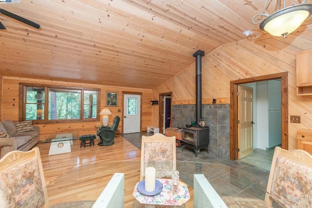 living room with lofted ceiling, a wood stove, wooden walls, and wooden ceiling