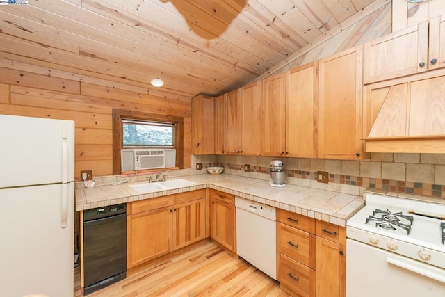 kitchen with white appliances, vaulted ceiling, light hardwood / wood-style floors, tile counters, and wood walls