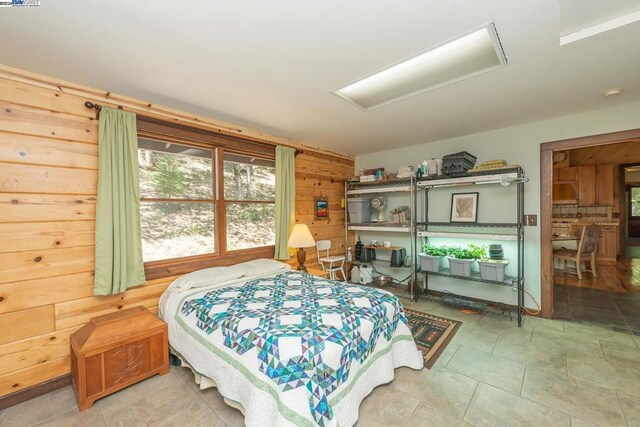 bedroom featuring tile patterned floors and wood walls