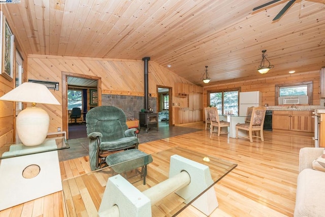 living room featuring wood ceiling, vaulted ceiling, light hardwood / wood-style flooring, a wood stove, and wood walls