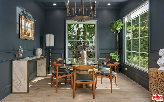 dining space featuring an inviting chandelier, ornamental molding, and light hardwood / wood-style floors