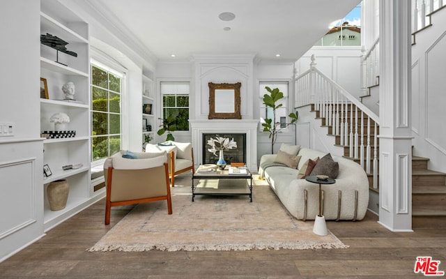 sitting room featuring crown molding, built in features, dark hardwood / wood-style flooring, and a fireplace