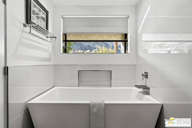 bathroom with a tub and tile walls