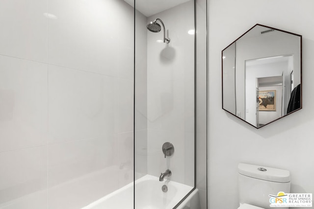 bathroom featuring tiled shower / bath combo and toilet