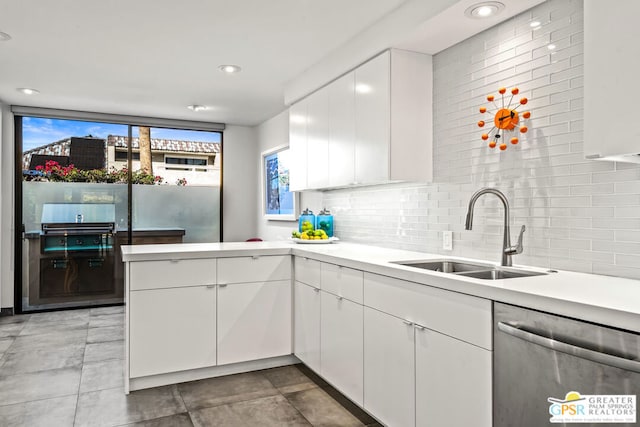 kitchen with dishwasher, sink, kitchen peninsula, decorative backsplash, and white cabinets