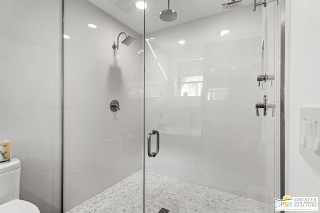 bathroom with a shower with shower door and toilet