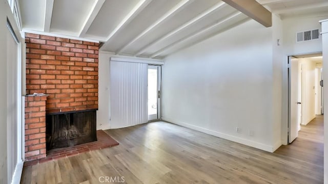 unfurnished living room featuring a fireplace, lofted ceiling with beams, and light hardwood / wood-style floors