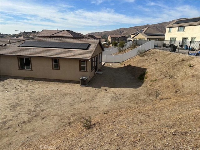 view of side of home with a mountain view, solar panels, and central AC