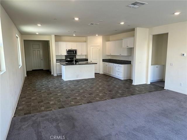 kitchen featuring white cabinetry, a kitchen island with sink, dark carpet, and appliances with stainless steel finishes