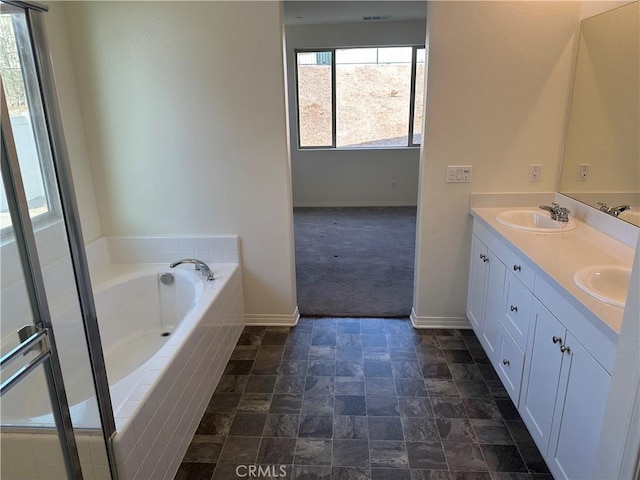 bathroom featuring a relaxing tiled tub and vanity