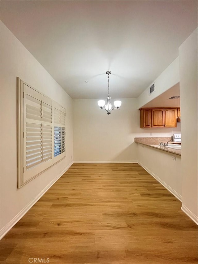 unfurnished dining area featuring light hardwood / wood-style floors and a chandelier