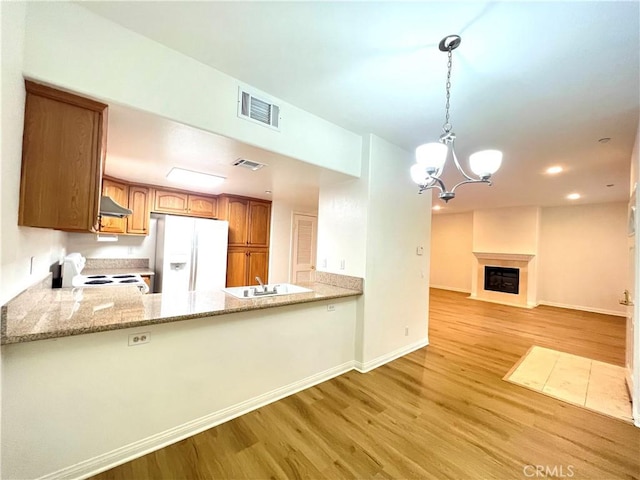 kitchen featuring kitchen peninsula, white appliances, light hardwood / wood-style flooring, and hanging light fixtures