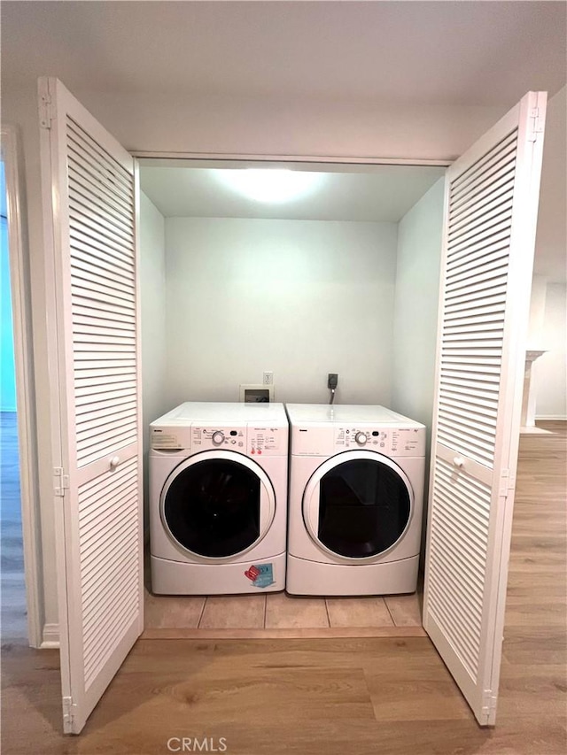 laundry room featuring separate washer and dryer and light hardwood / wood-style flooring