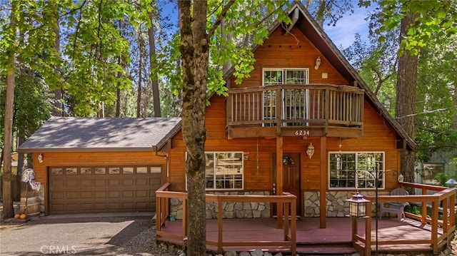 exterior space featuring a garage, stone siding, a shingled roof, and a balcony