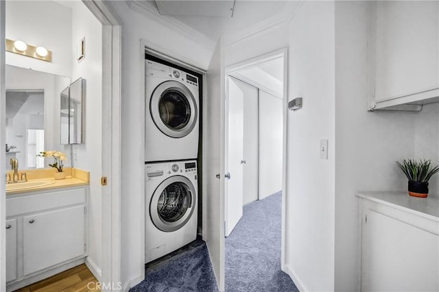 laundry area featuring carpet flooring, stacked washer / dryer, sink, and ornamental molding