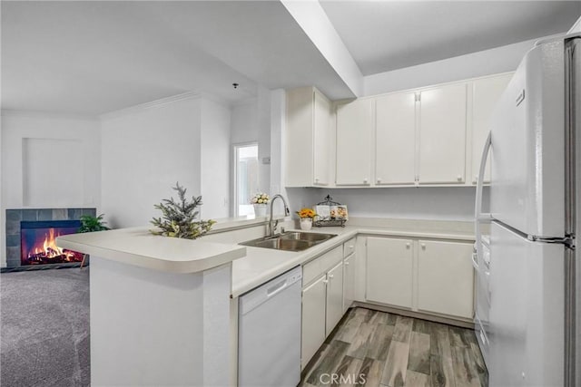 kitchen featuring kitchen peninsula, sink, white cabinets, and white appliances