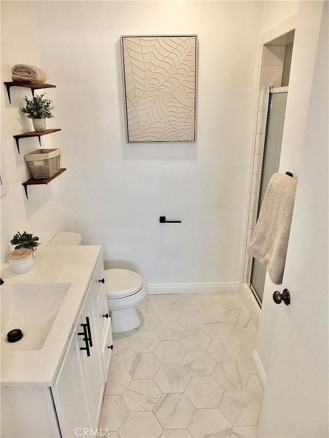 bathroom featuring a shower with door, vanity, and toilet