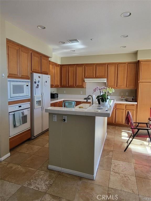 kitchen featuring white appliances and a kitchen island with sink