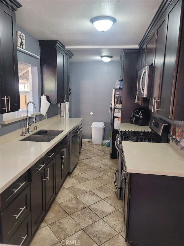 kitchen featuring a textured ceiling, dark brown cabinets, sink, and appliances with stainless steel finishes