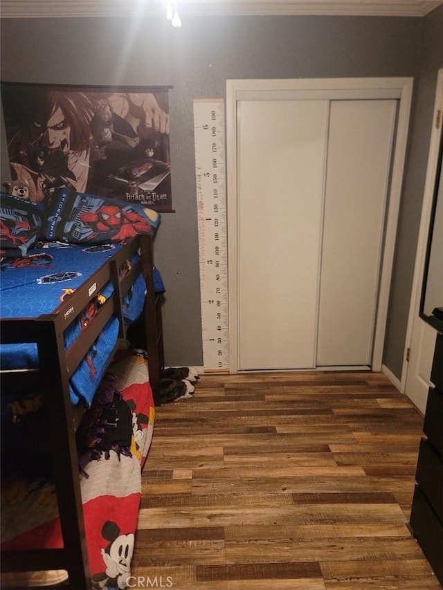 bedroom with wood-type flooring, a closet, and crown molding