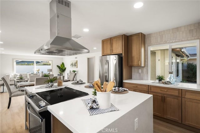 kitchen featuring appliances with stainless steel finishes, brown cabinets, wood finished floors, extractor fan, and light countertops