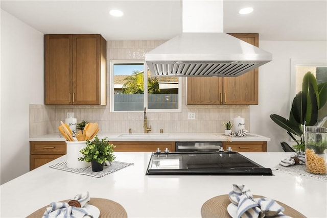 kitchen with island range hood, decorative backsplash, a sink, and light countertops