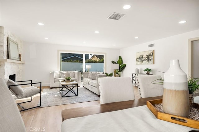 living room featuring light wood-type flooring, visible vents, a fireplace, and recessed lighting