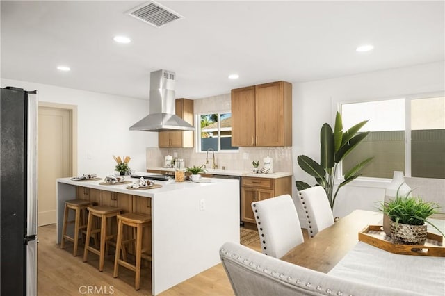 kitchen featuring island range hood, a kitchen island, visible vents, freestanding refrigerator, and tasteful backsplash