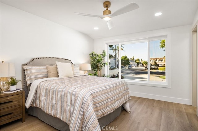 bedroom with ceiling fan, vaulted ceiling, multiple windows, and light wood-type flooring