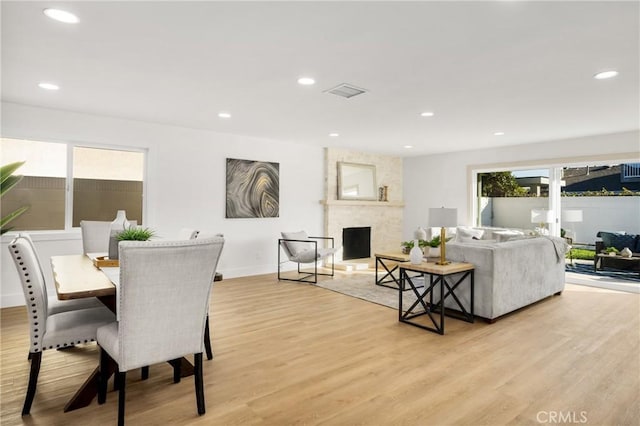 dining area featuring light wood-type flooring, a large fireplace, visible vents, and recessed lighting