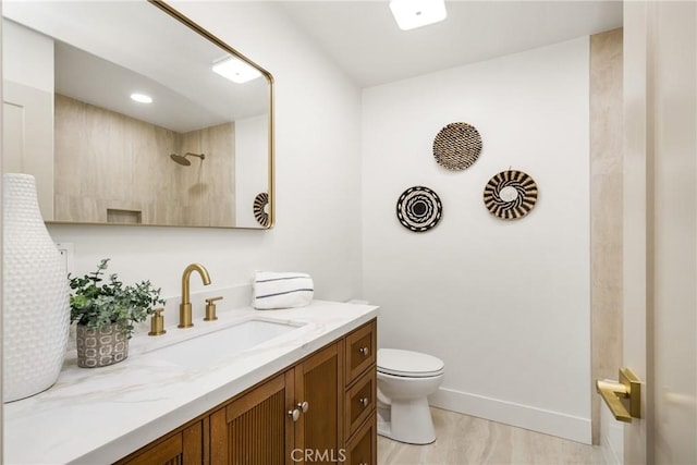 bathroom featuring toilet, walk in shower, vanity, and baseboards