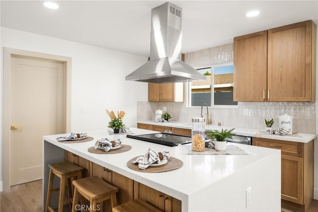 kitchen featuring tasteful backsplash, a breakfast bar, island exhaust hood, and a kitchen island