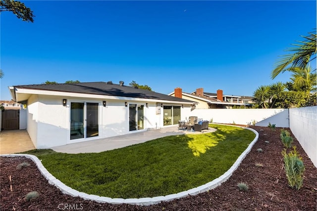 back of house featuring a yard, a fenced backyard, a patio, and stucco siding